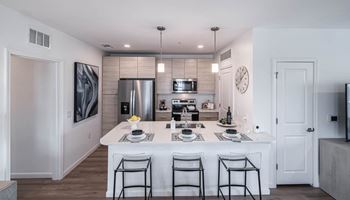 A kitchen with a large island and a stainless steel refrigerator